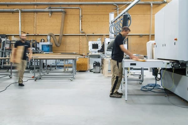 Stockfoto von zwei Mitarbeitern einer Tischlerei an einer CNC-Maschine